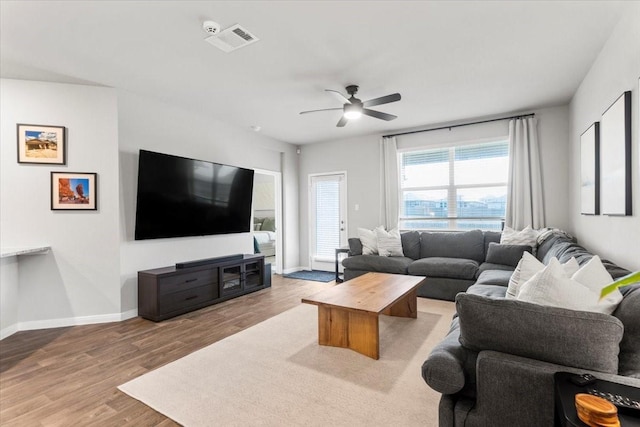 living room featuring visible vents, wood finished floors, baseboards, and ceiling fan