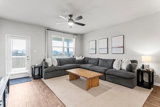 living area with baseboards, a ceiling fan, and wood finished floors