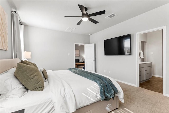 carpeted bedroom featuring visible vents, baseboards, ensuite bath, and a ceiling fan