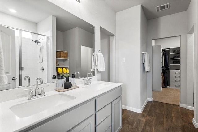 full bathroom featuring visible vents, a shower stall, wood finished floors, and a sink