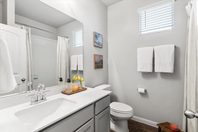 bathroom with vanity, wood finished floors, baseboards, curtained shower, and toilet