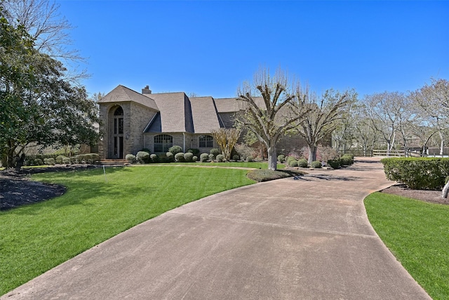 view of community with a lawn and curved driveway