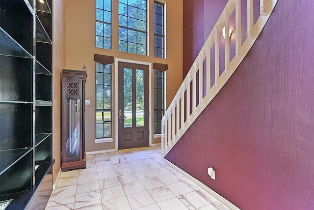 entrance foyer with stairway, baseboards, marble finish floor, and a towering ceiling