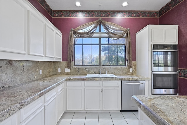 kitchen featuring tasteful backsplash, white cabinets, appliances with stainless steel finishes, and a sink