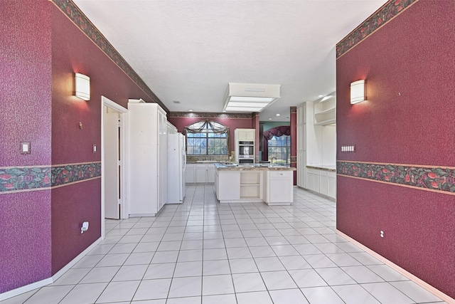 kitchen with light countertops, light tile patterned floors, freestanding refrigerator, white cabinetry, and open shelves