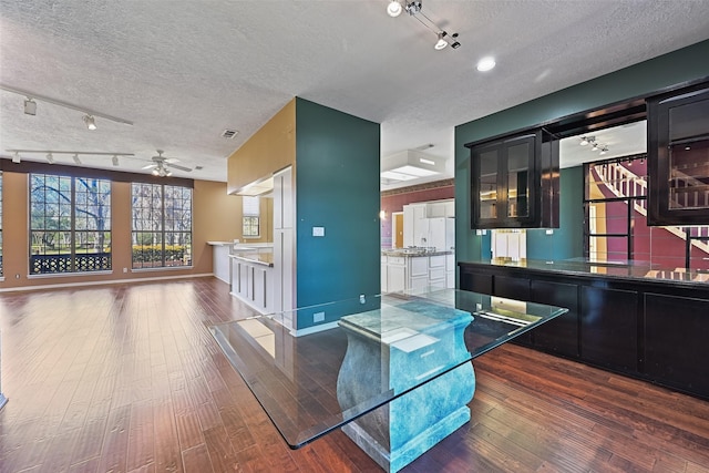 kitchen with a textured ceiling, glass insert cabinets, a ceiling fan, and wood finished floors