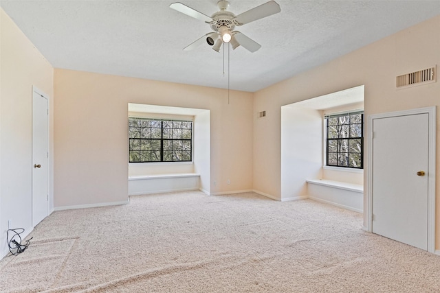 empty room featuring visible vents, plenty of natural light, carpet, and a ceiling fan