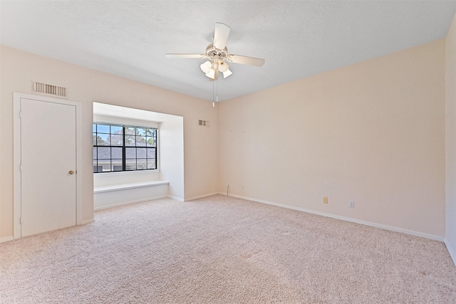 carpeted empty room featuring visible vents, baseboards, and a ceiling fan