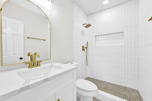 full bathroom with vanity, toilet, and tiled shower