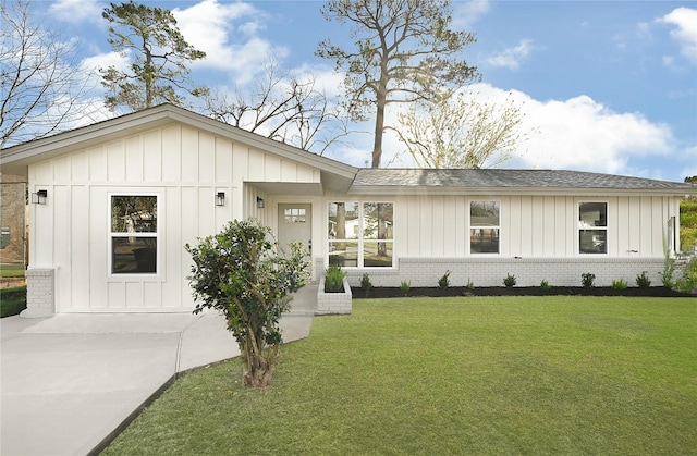 modern farmhouse style home featuring brick siding, board and batten siding, a front lawn, and roof with shingles