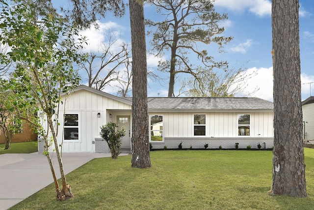 modern farmhouse style home featuring brick siding, board and batten siding, a front yard, and roof with shingles