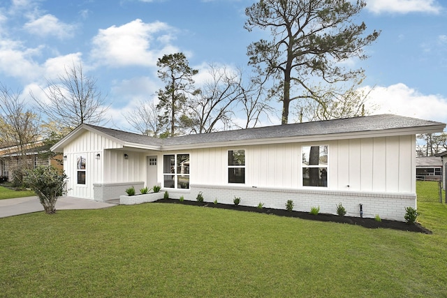 modern farmhouse featuring a front lawn, brick siding, board and batten siding, and a shingled roof