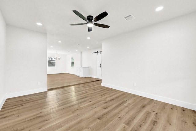 unfurnished living room featuring recessed lighting, baseboards, light wood-style floors, and ceiling fan with notable chandelier