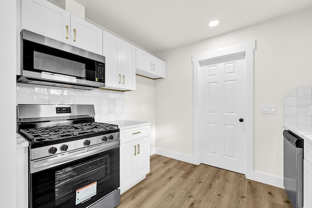 kitchen featuring backsplash, light wood-style floors, appliances with stainless steel finishes, white cabinets, and light countertops