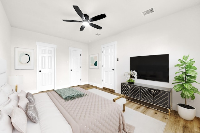 bedroom featuring baseboards, wood finished floors, visible vents, and ceiling fan