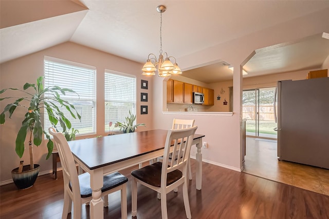 dining room with baseboards, lofted ceiling, a notable chandelier, and wood finished floors