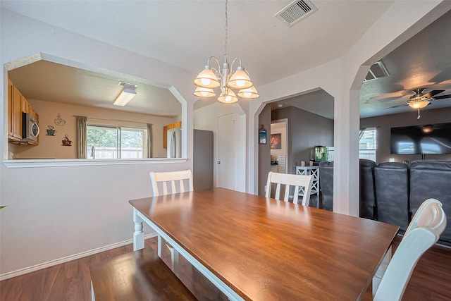 dining space with baseboards, visible vents, dark wood-style flooring, arched walkways, and ceiling fan with notable chandelier