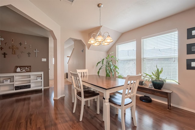 dining area featuring dark wood-style floors, arched walkways, baseboards, and an inviting chandelier