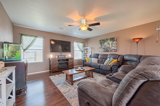 living area with baseboards, dark wood-style floors, visible vents, and ceiling fan