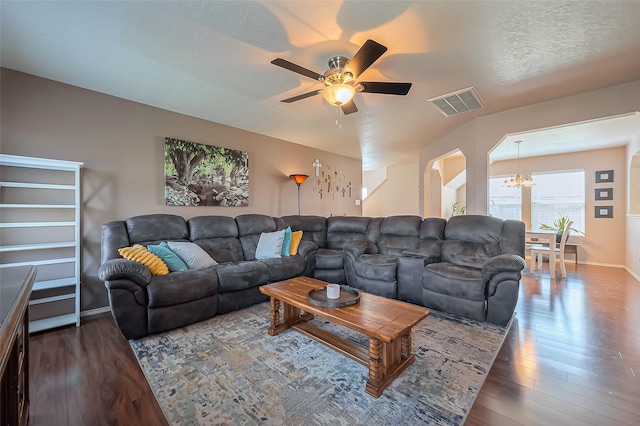 living room with wood finished floors, baseboards, visible vents, arched walkways, and ceiling fan with notable chandelier