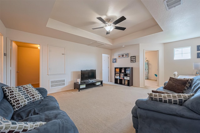 living room featuring a tray ceiling, light colored carpet, and ceiling fan