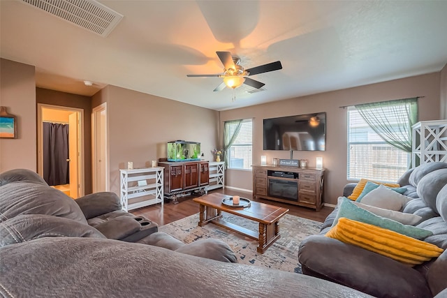 living area with visible vents, baseboards, ceiling fan, and dark wood-style flooring