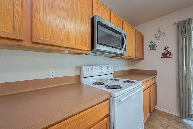 kitchen with stainless steel microwave, electric range, light countertops, and baseboards