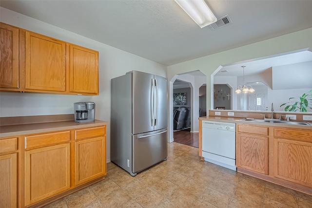 kitchen with visible vents, dishwasher, freestanding refrigerator, arched walkways, and a sink