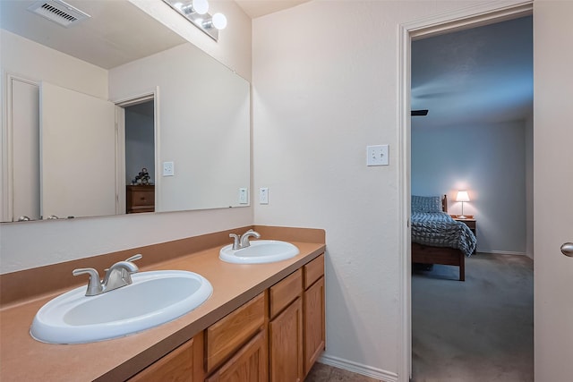 ensuite bathroom featuring a sink, visible vents, connected bathroom, and double vanity