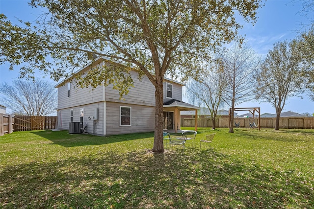 back of property with central air condition unit, a lawn, and a fenced backyard