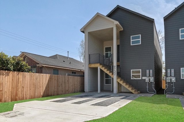 rear view of property with a yard, stairs, and fence