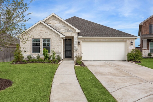 view of front of property featuring an attached garage, roof with shingles, concrete driveway, and a front lawn