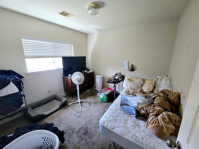 bedroom featuring visible vents, carpet, and a textured ceiling