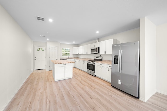 kitchen with visible vents, a kitchen island, stainless steel appliances, white cabinets, and light countertops