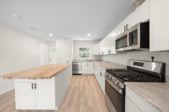 kitchen with white cabinetry, light wood finished floors, appliances with stainless steel finishes, and a kitchen island