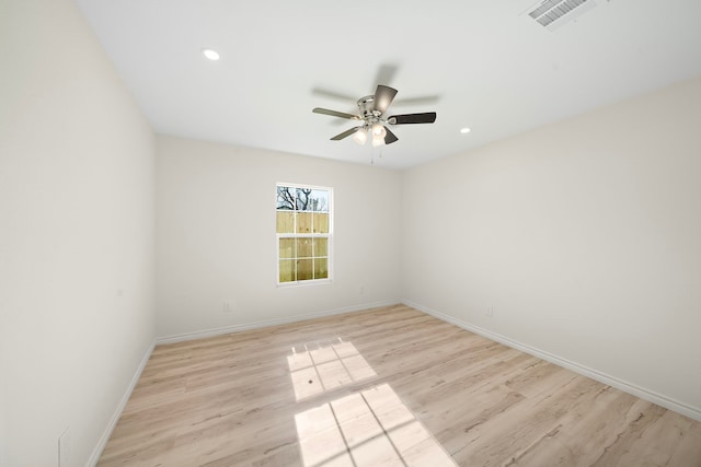 spare room with light wood-type flooring, visible vents, baseboards, and ceiling fan