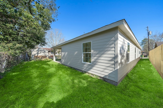 view of side of home with a lawn and fence