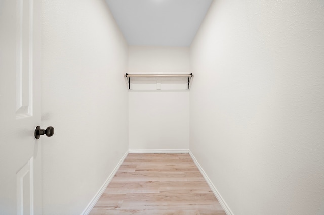 walk in closet with light wood-style floors