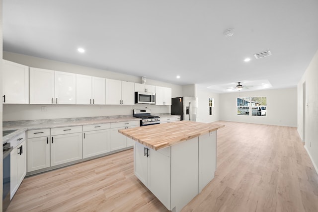 kitchen featuring visible vents, butcher block countertops, a ceiling fan, white cabinetry, and stainless steel appliances