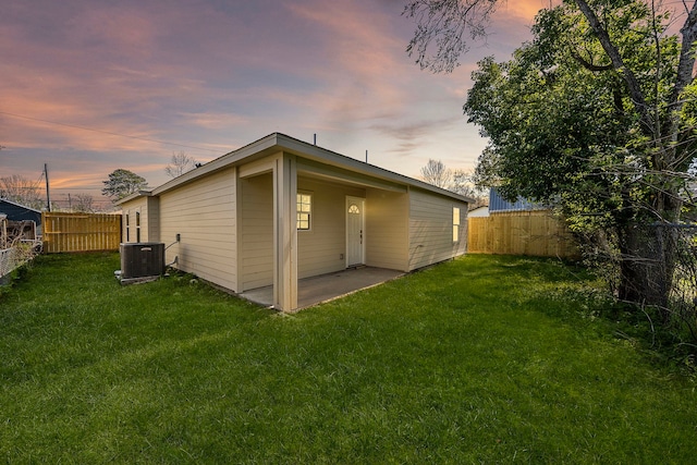 rear view of property with a patio area, central AC unit, a lawn, and a fenced backyard