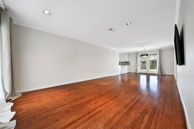 unfurnished living room featuring crown molding, dark wood-style floors, and baseboards