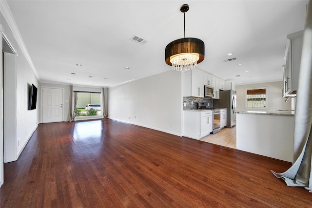 unfurnished living room featuring a healthy amount of sunlight, ornamental molding, and light wood finished floors