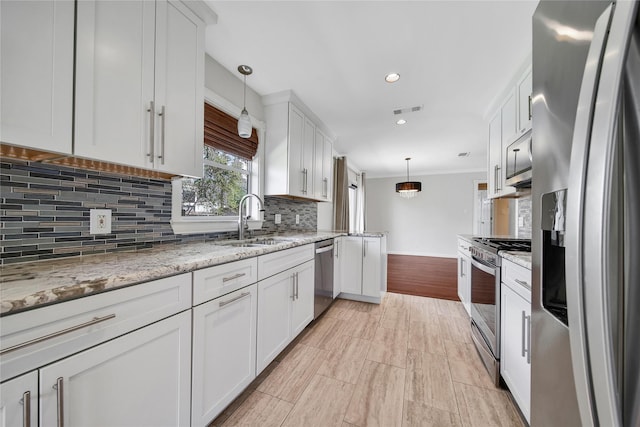 kitchen featuring visible vents, a sink, appliances with stainless steel finishes, white cabinets, and decorative backsplash