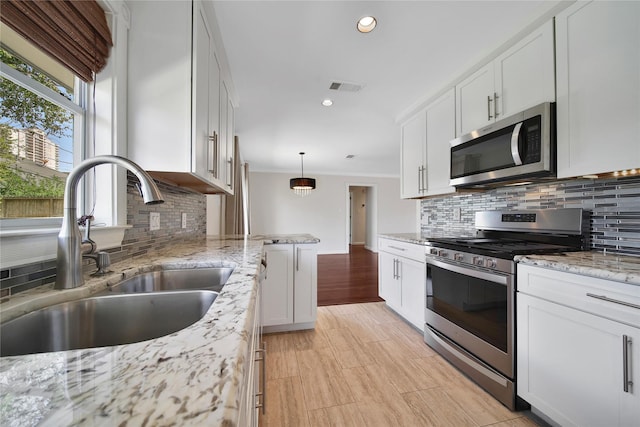 kitchen with light stone countertops, visible vents, a sink, stainless steel appliances, and white cabinetry