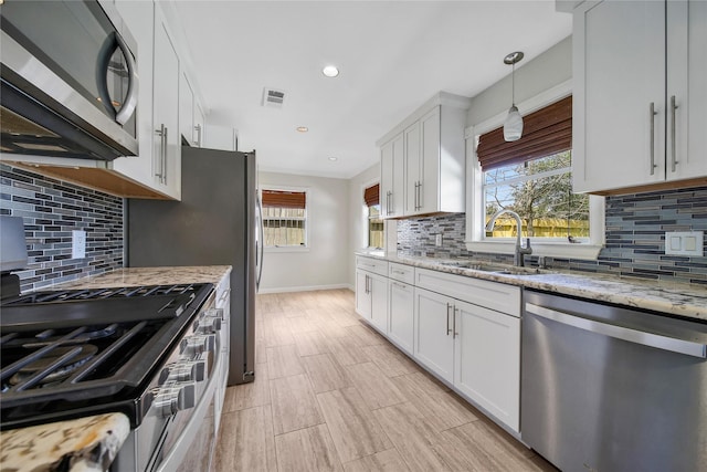 kitchen with light stone countertops, visible vents, a sink, stainless steel appliances, and white cabinets