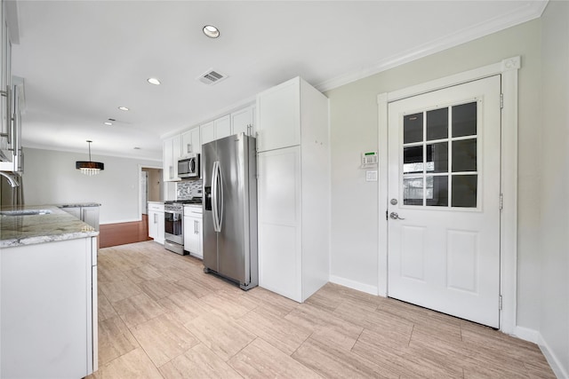 kitchen featuring visible vents, a sink, appliances with stainless steel finishes, white cabinetry, and crown molding