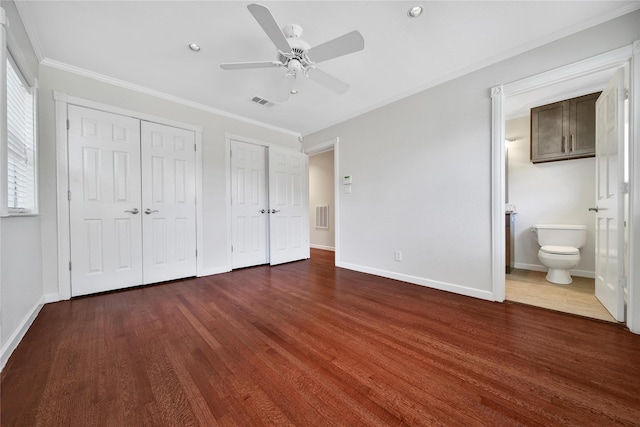 unfurnished bedroom with baseboards, multiple closets, wood finished floors, and ornamental molding