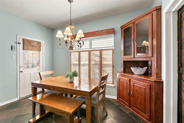 dining area featuring baseboards, stone tile floors, and a chandelier