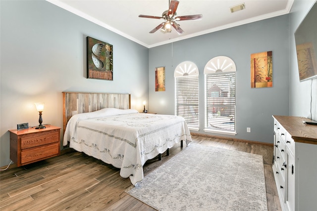 bedroom featuring visible vents, light wood-style flooring, a ceiling fan, and ornamental molding