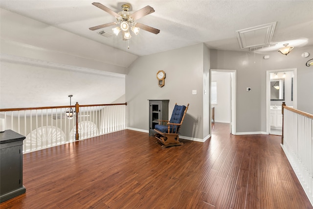 sitting room featuring visible vents, attic access, lofted ceiling, wood finished floors, and a ceiling fan